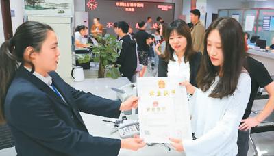 河北省承德市網(wǎng)絡(luò)代購經(jīng)營者陳晨(右)從工作人員手中接過帶有統(tǒng)一社會(huì)信用代碼的營業(yè)執(zhí)照。 劉環(huán)宇攝(人民圖片)