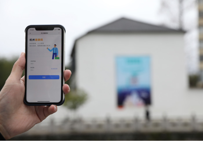 在浙江省杭州市臨安區(qū)天目山鎮(zhèn)，一名居民在“杭州健康碼”海報上掃碼申領(lǐng)個人二維碼。新華社發(fā)